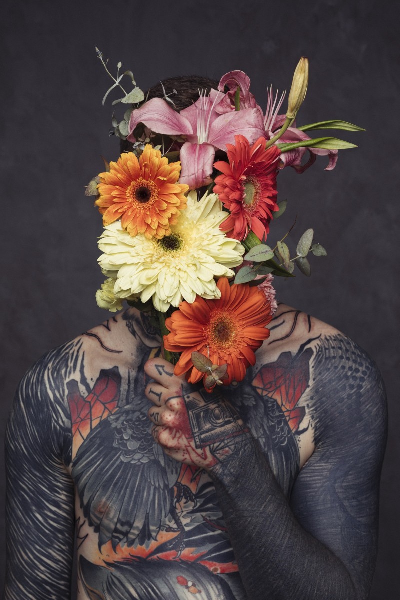 Hombre tatuado agarrando ramo de flores