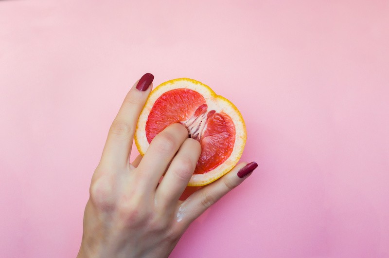 Female hand touching grapefruit
