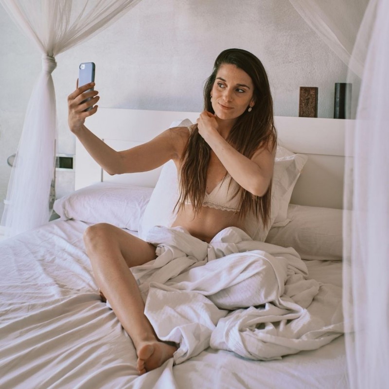 donna su letto fa video striptease con smartphone