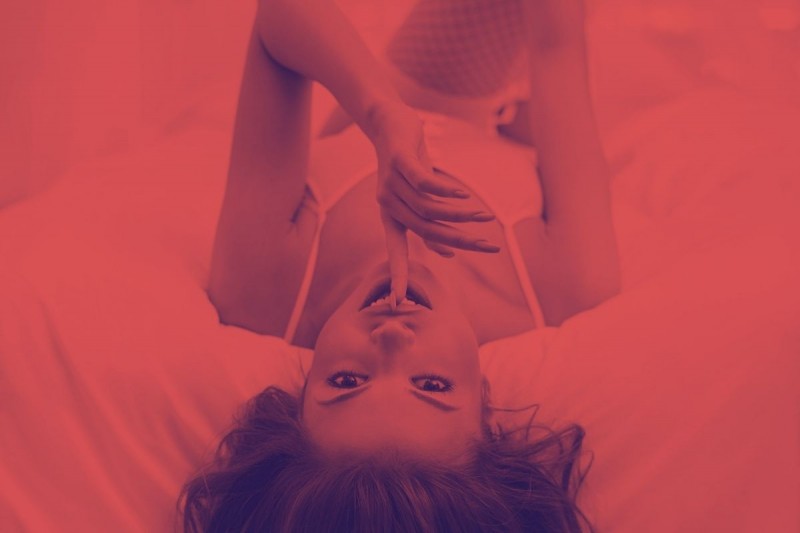 donna sexy su letto indica con dito di fare silenzio