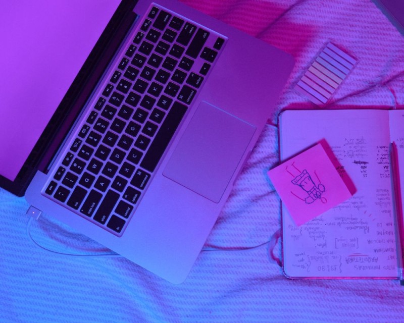 portátil en la cama con cuaderno de notas
