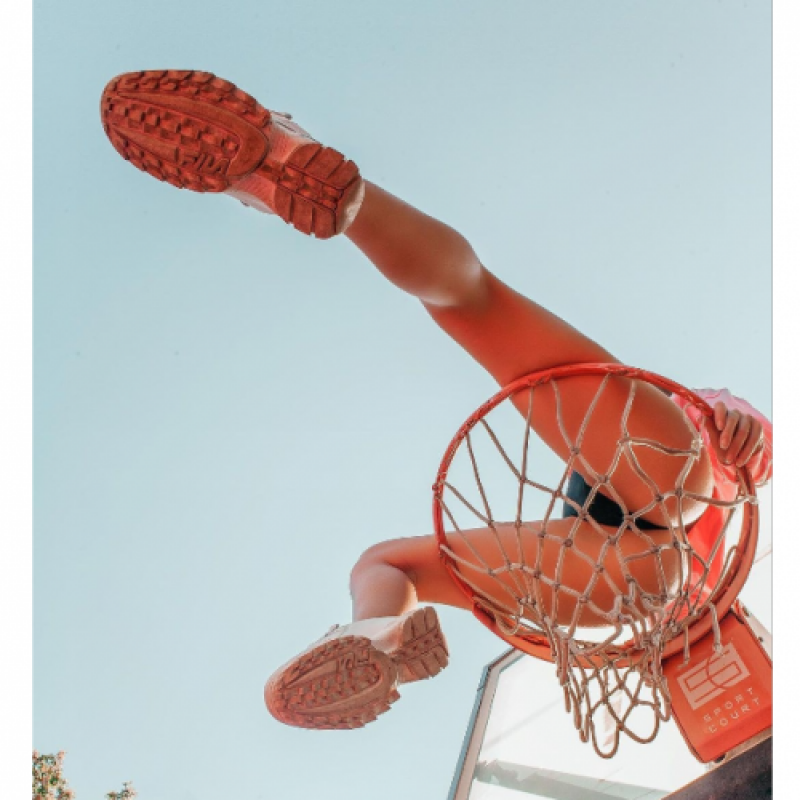 image d’une fille assise dans un panier de basket vu d’en bas