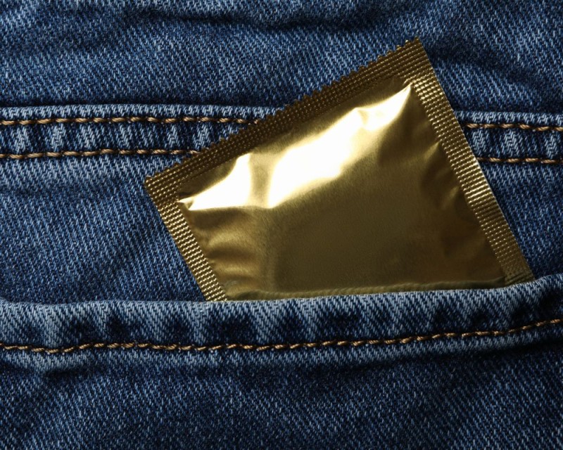 un preservativo se escapa del bolsillo de unos vaqueros