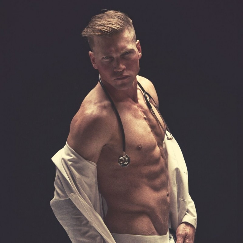 man stripping with shirt semi open in black background