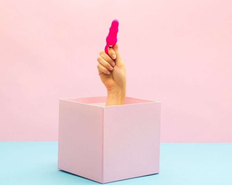 hand coming out of a box while holding a butt-plug
