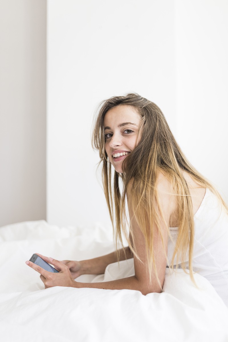 Mujer teniendo sexting en su cama