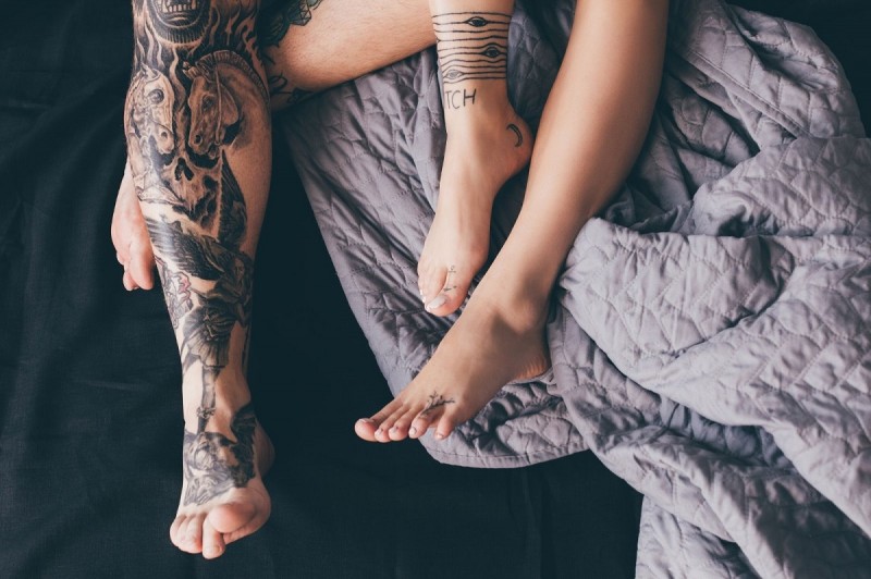 Piernas tatuadas de pareja en la cama
