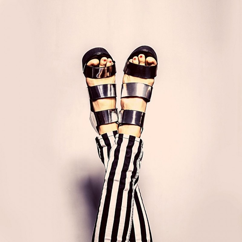The end of a woman's crossed legs and feet in striped trousers and black heeled sandals