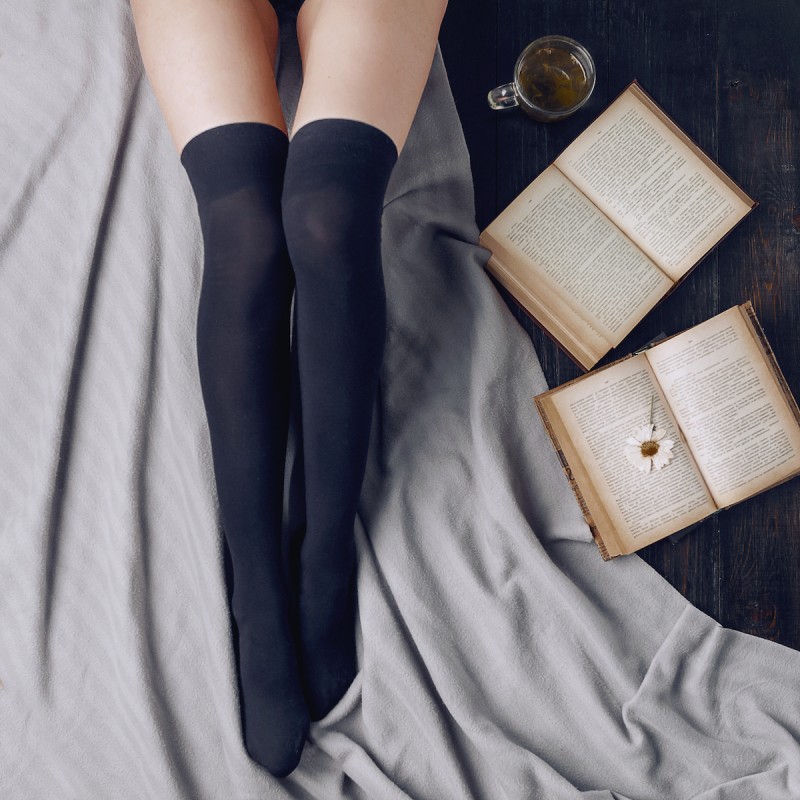 woman legs lying on bed with books