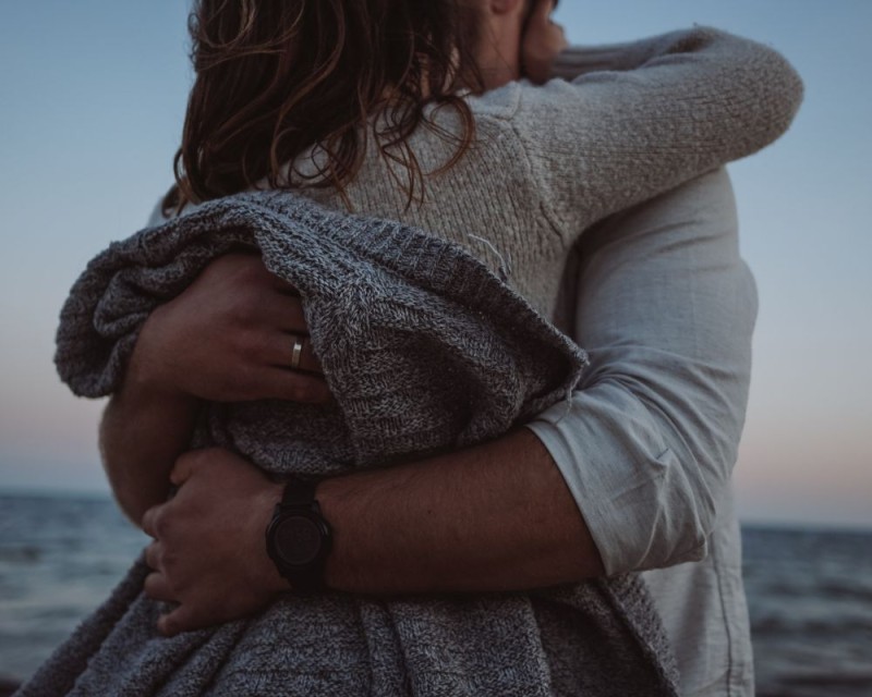 pareja se abraza junto al mar al atardecer